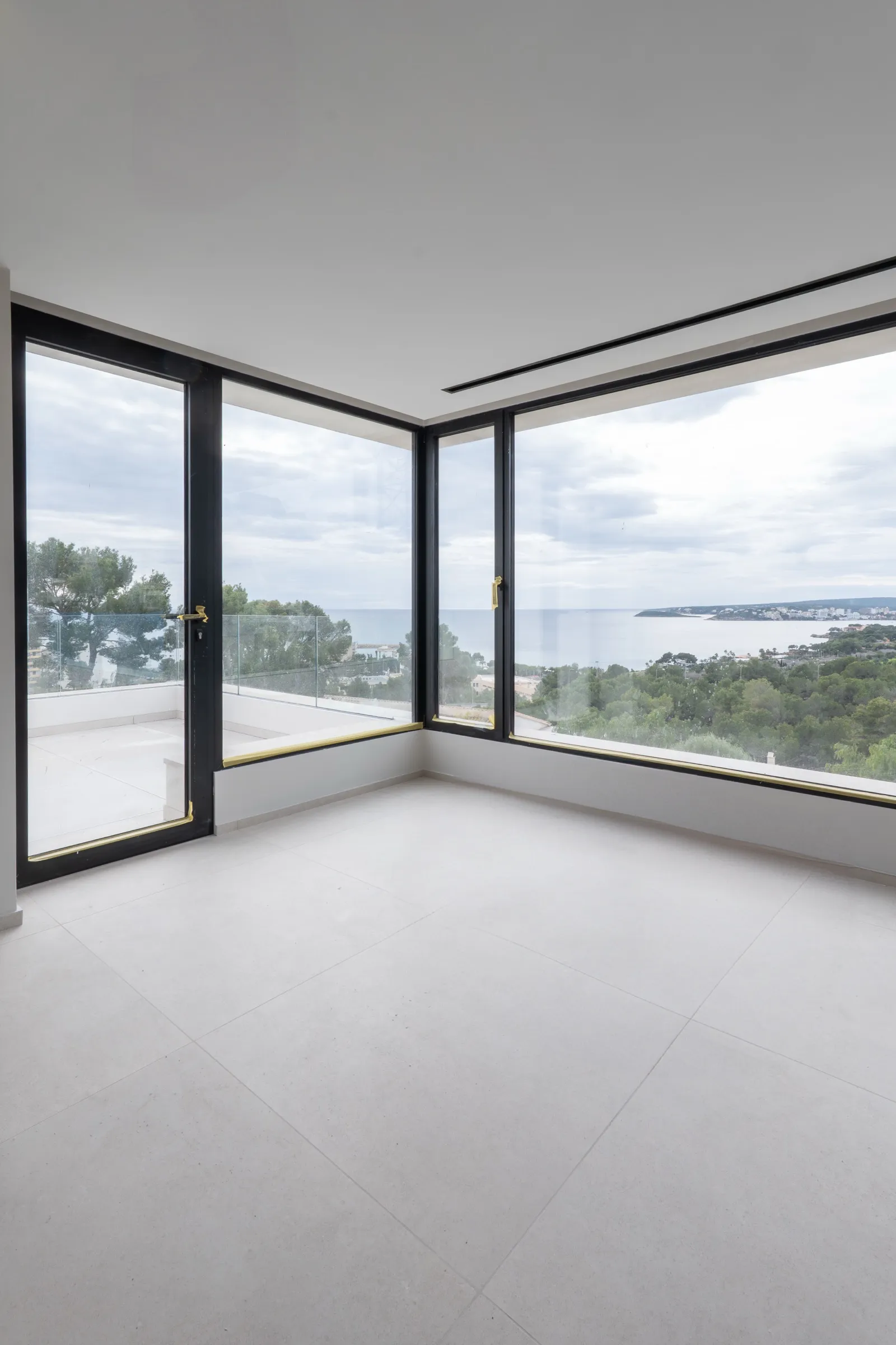 Dormitorio con falso techo continuo y ventanales panorámicos al mar